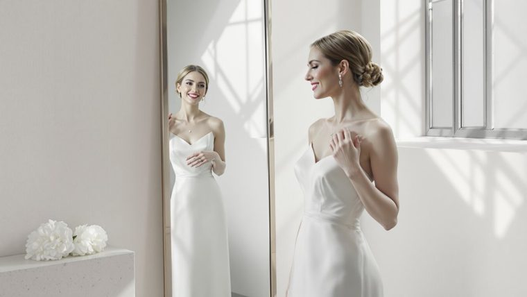 Beautiful bride in elegant wedding dress looking at her reflection.