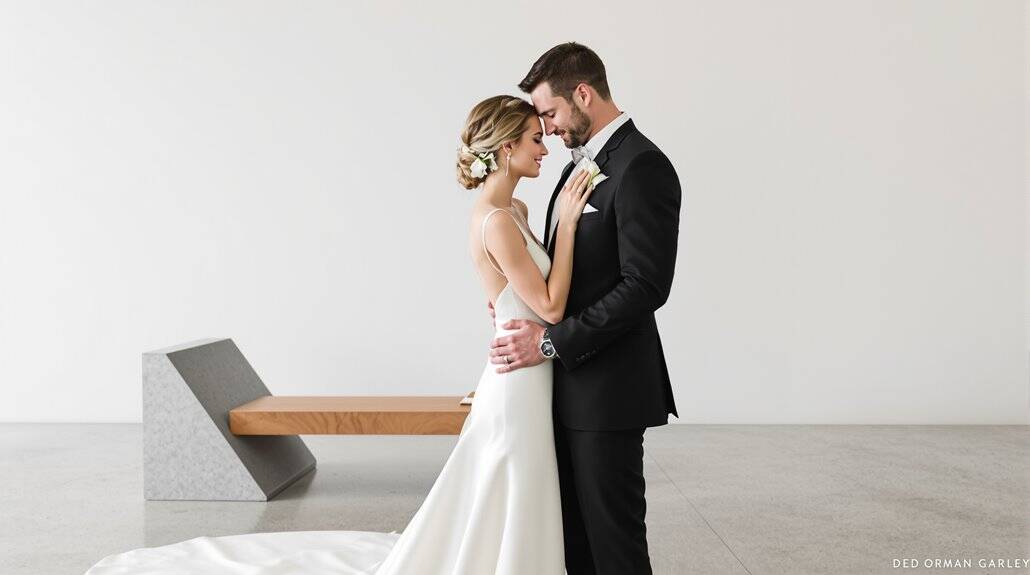 Elegant wedding couple embracing in minimalist setting, celebrating love and commitment.