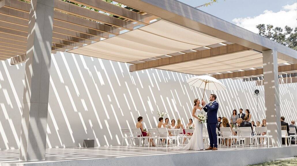 Bride and groom exchanging vows under a modern outdoor canopy.