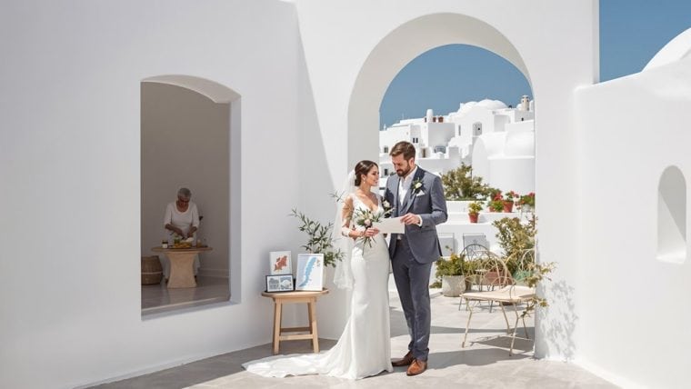 Elegant wedding couple exchanging vows in Santorini's iconic white architecture.