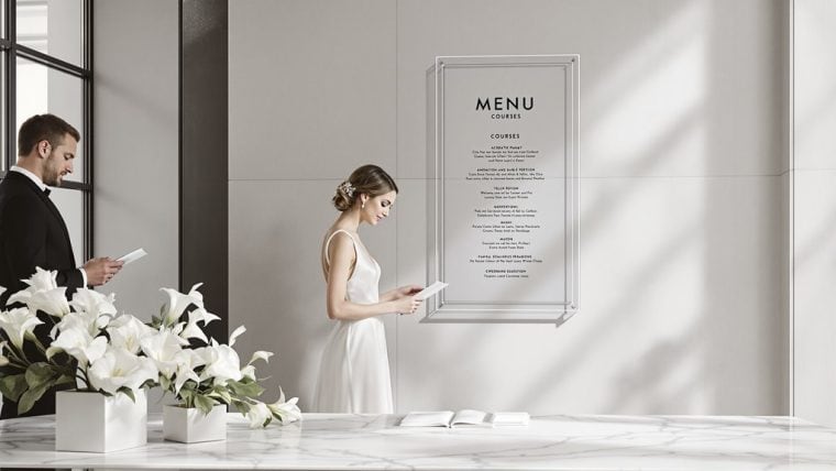 Elegant wedding couple reading menu at reception with floral decor.