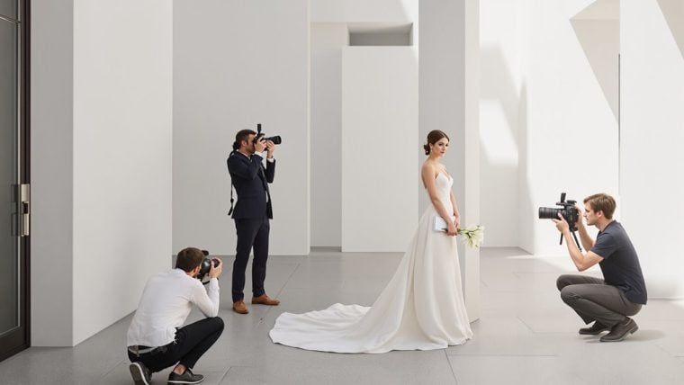 Bride posing for wedding photos with photographers in modern studio setting.