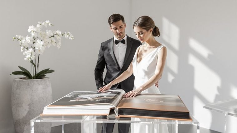 Elegant wedding couple looking at wedding album, stylish bride and groom in modern setting.