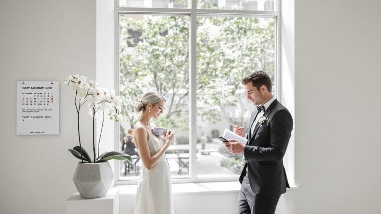 Elegant wedding ceremony with bride and groom reading vows by a large window.