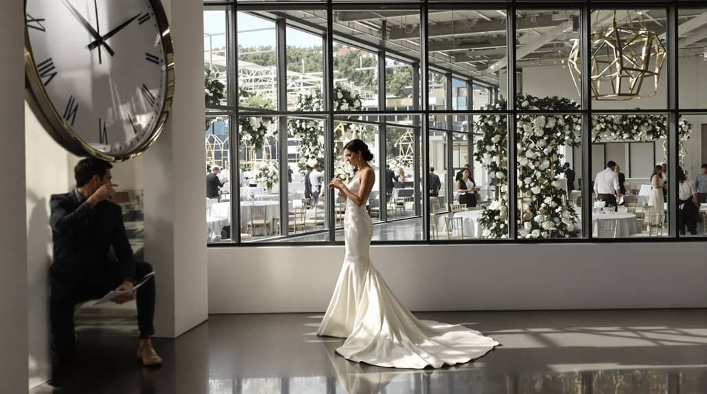 Bride in elegant wedding dress at contemporary venue with large glass windows.